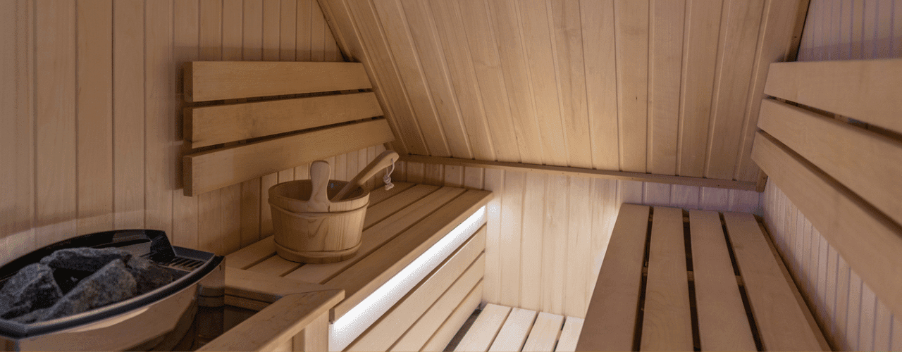 Electric sauna room with warm wooden walls and a sink for added comfort.